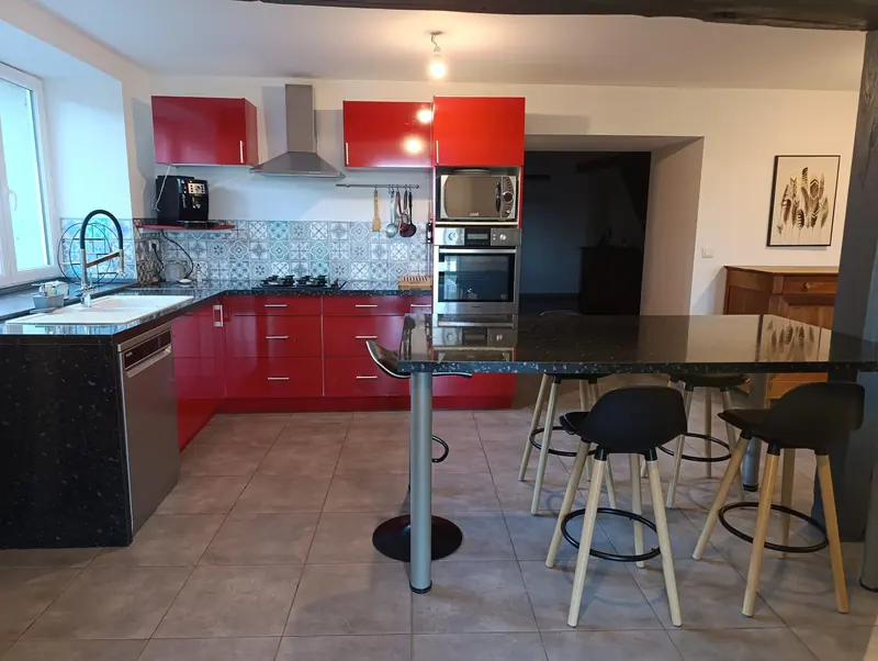 La cuisine rouge avec son îlot et ses tabourets hauts
