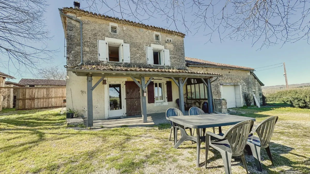 La terrasse couverte et la table de jardin devant la maison