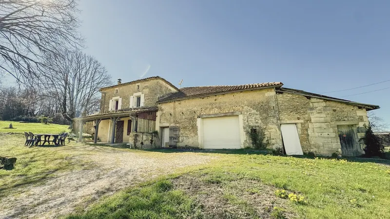 La pelouse au soleil devant la grange et la maison
