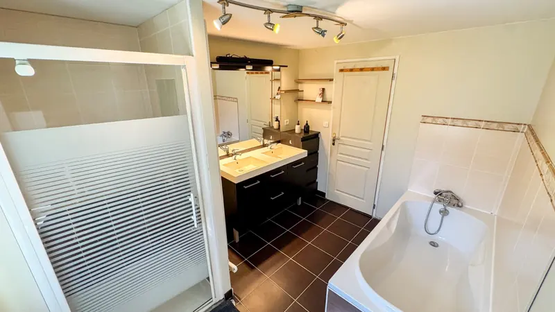 Salle d'eau avec baignoire, double vasque et douche